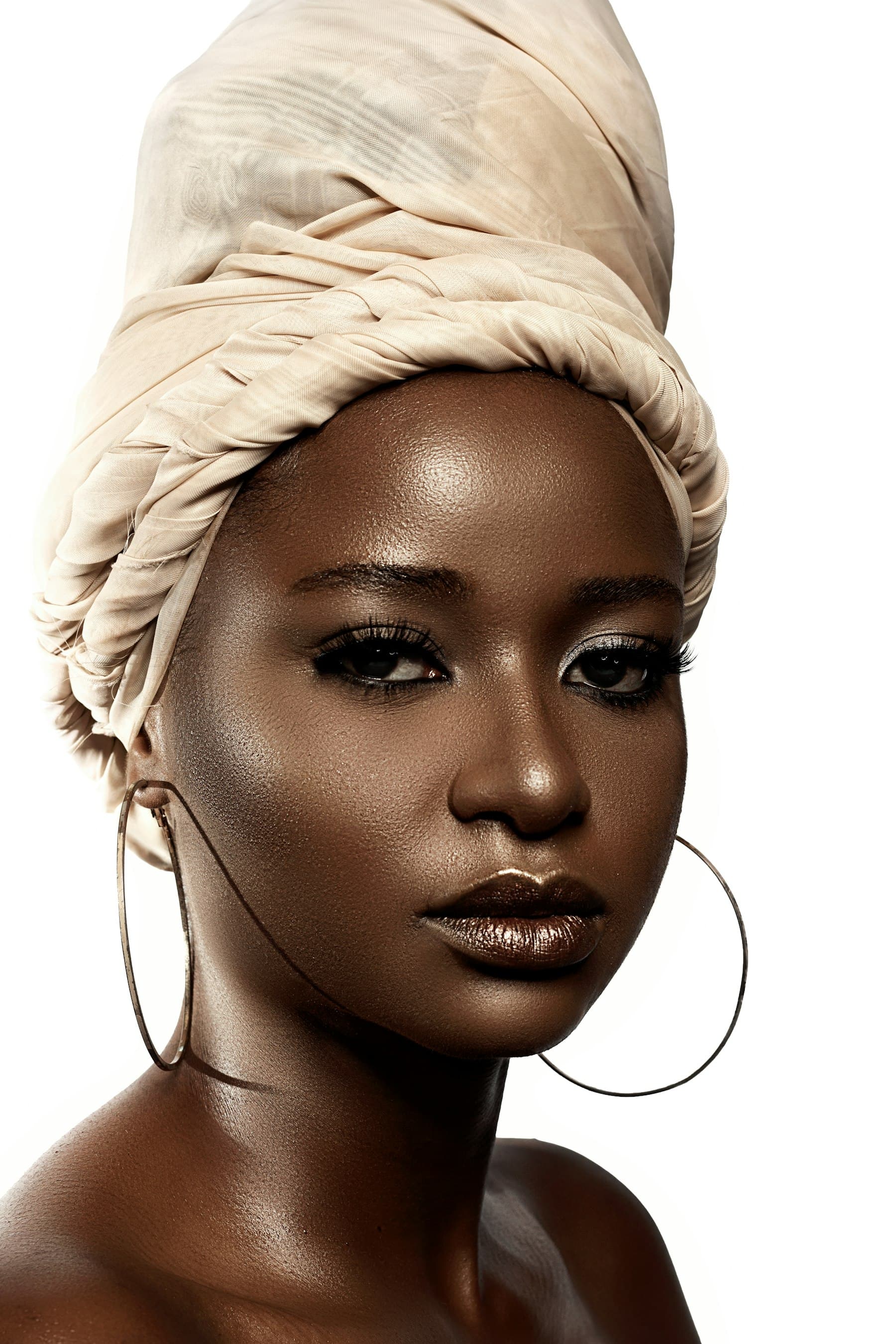 A client wearing a full lash set and gold hoop earrings