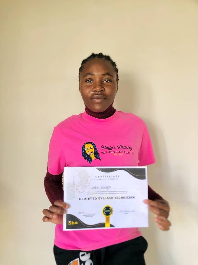 A graduate holding her Certified Eyelash Technician certificate